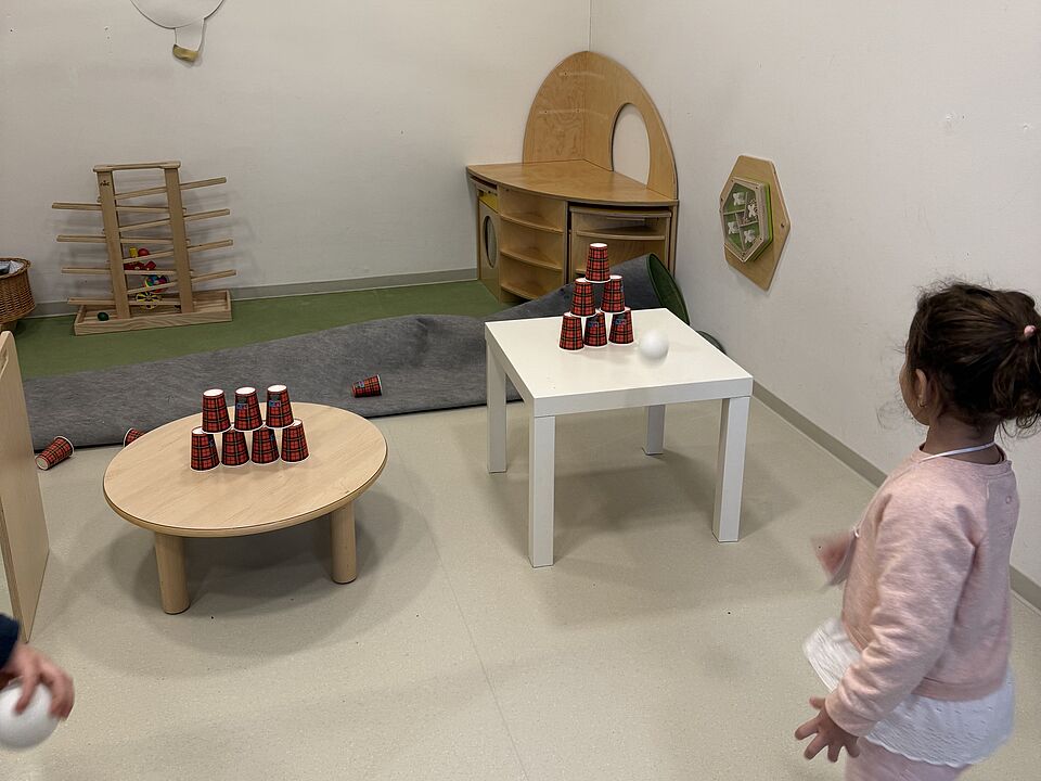 6875 Ein Mädchen wirft mit Säcken auf gestapelte Dosen/Becher.