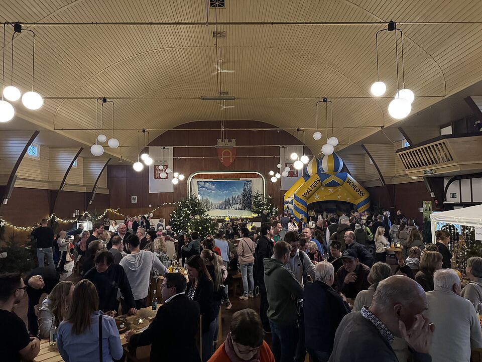 IMG 8390 Ein Blick in die volle Schützenhalle. Man sieht sehr viele Menschen. Die Halle ist weihnachtlich eingerichtet.