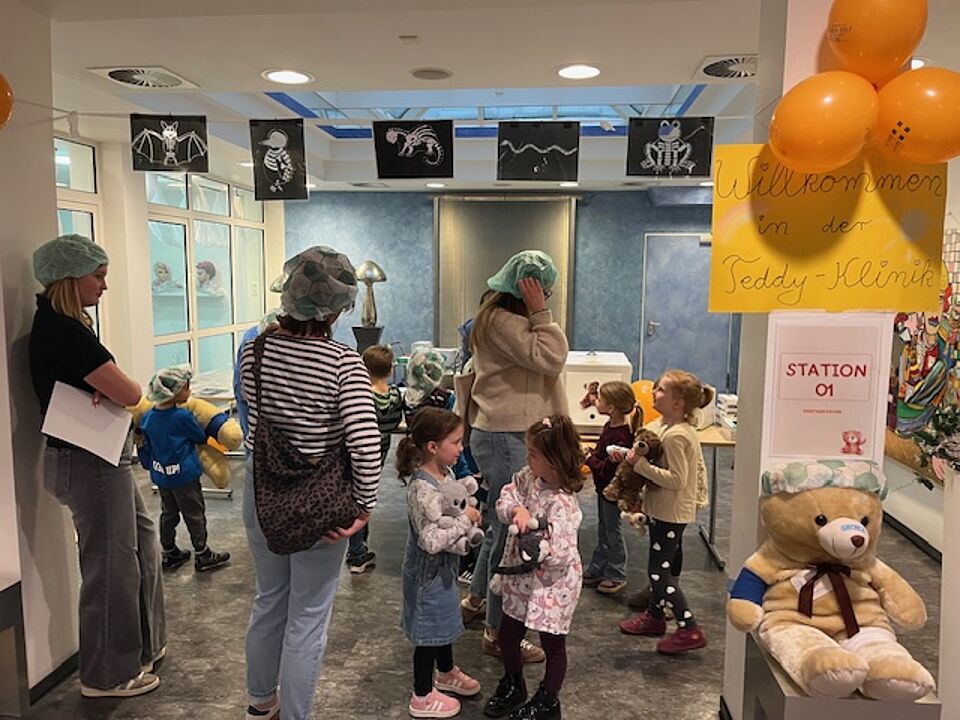 Kinder und Erzieherinnen stehen in der Teddyklinik, in der die Kuscheltiere der Kinder behandelt werden.