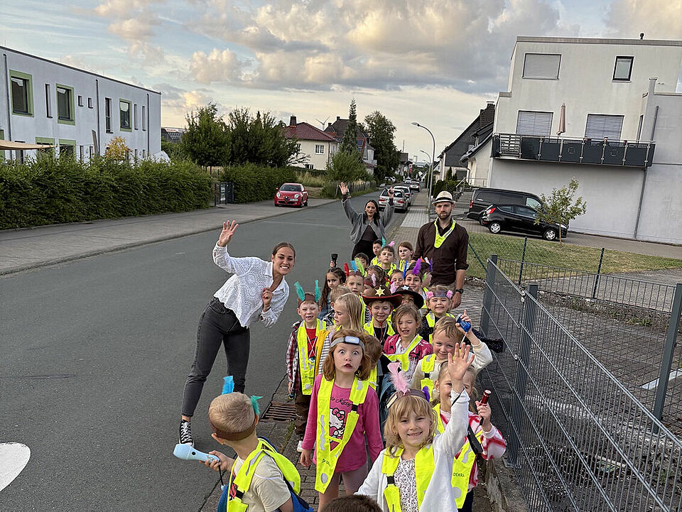 Die Gruppe der Einsteinkids mit Erzieherinnen und Erzieher lachen und winken gut gelaunt in die Kamera