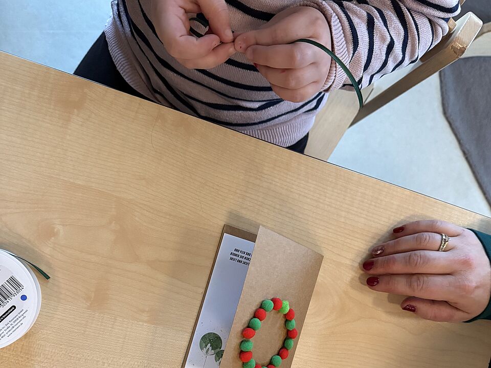 6865 Ein Kind bastelt an einer Kette für seine selbstgemachte Weihnachtskarte.