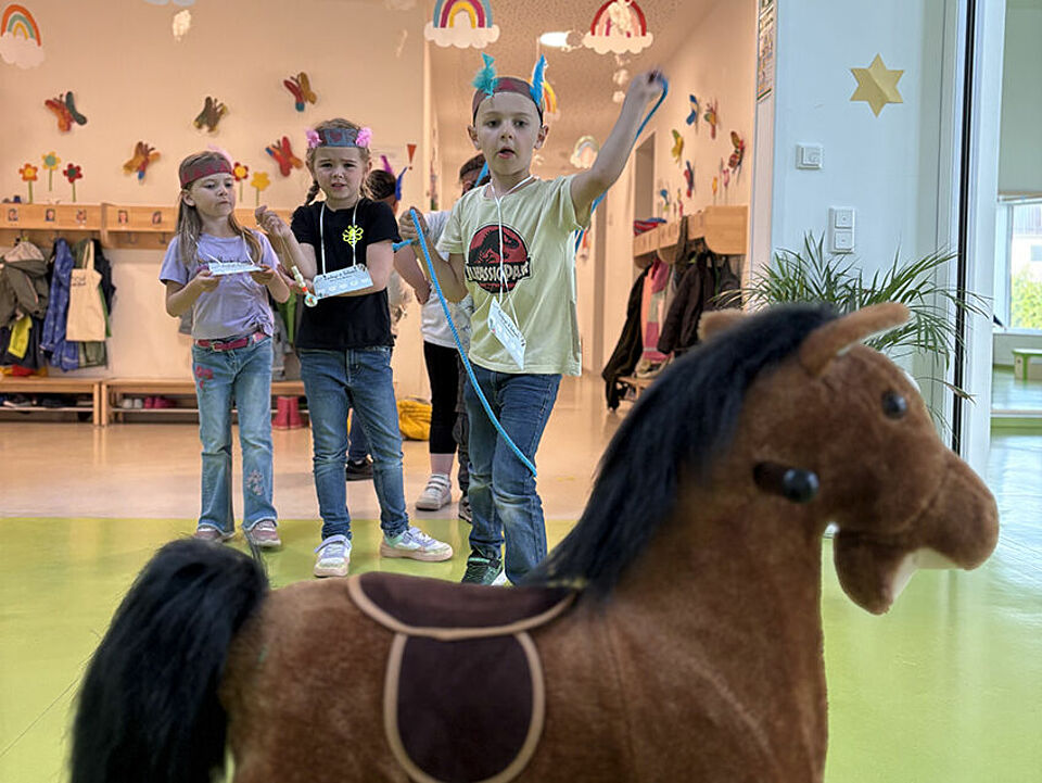 Ein Junge versucht ein Lasso um den Kopf eines Schaukelpferds zu werfen.