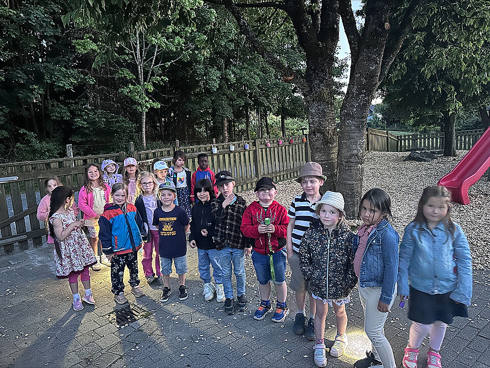 Die 19 Vorschulkinder stehen auf dem Außengelände der Kita und warten auf den Beginn ihrer Nachtwanderung. 