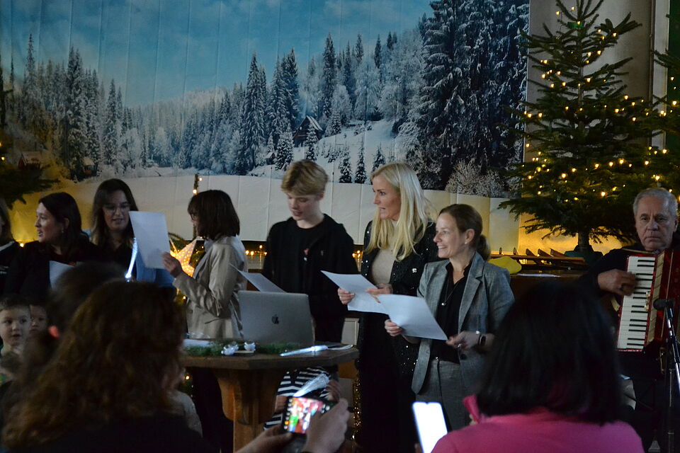 DSC0394 Eine menge Frauen die auf der Bühne mit Mirkofon stehen und Zettel halten. Eventuell sind sie am singen.