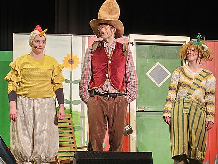 Das Huhn Prillan, Petterson und Findus stehen in einer Szene des Stücks nebeneinander auf der Bühne.
